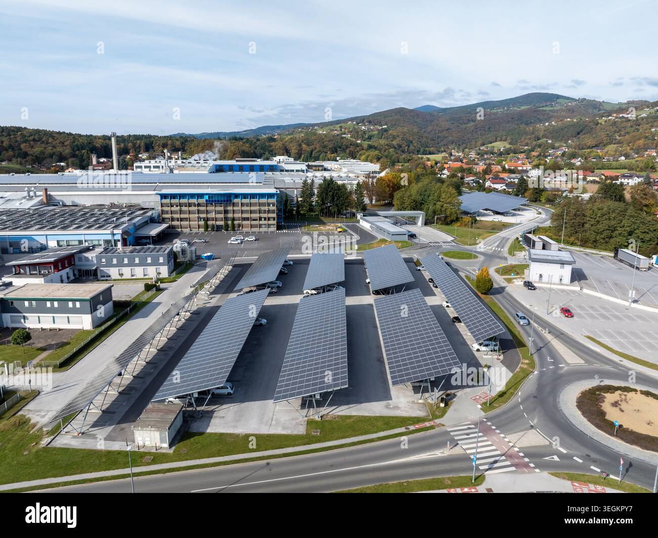 Drone capture des panneaux solaires installés dans un parking avec des bâtiments et des arbres en vue pendant la journée. Banque D'Images