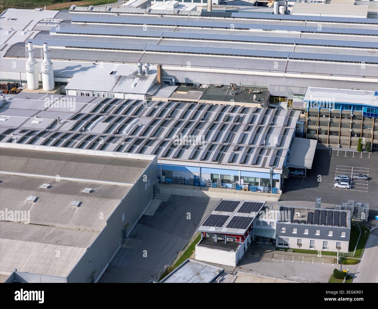 Vue aérienne d'un grand complexe industriel avec panneaux solaires sur les toits et parking visible à proximité pendant les heures de jour. Banque D'Images