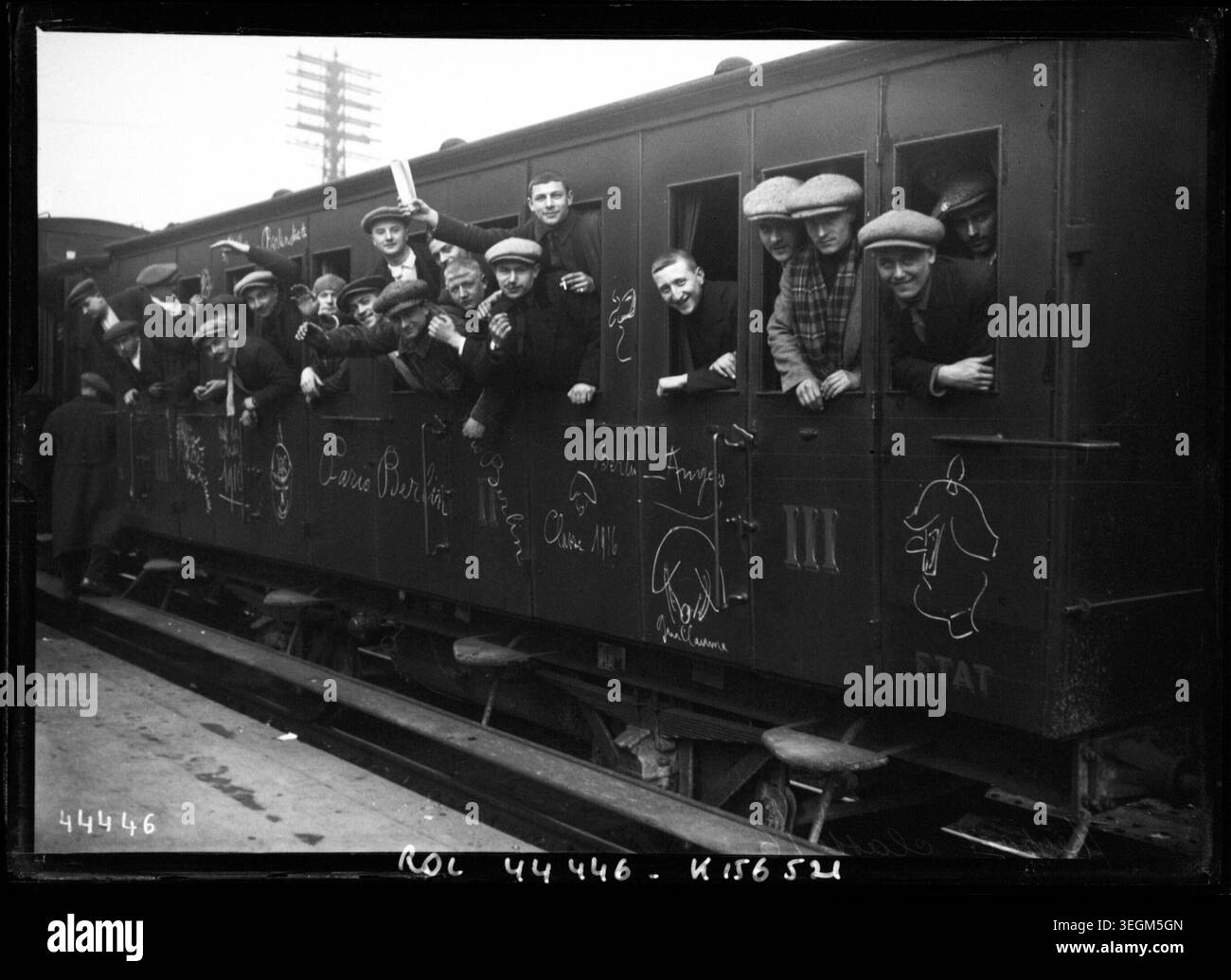 Des jeunes hommes de la classe militaire 16 se penchent par les fenêtres des trains à la gare Montparnasse à Paris en 1915. La photographie de presse rapporte leur départ pour la mobilisation pendant la première Guerre mondiale et l'environnement ferroviaire. Banque D'Images