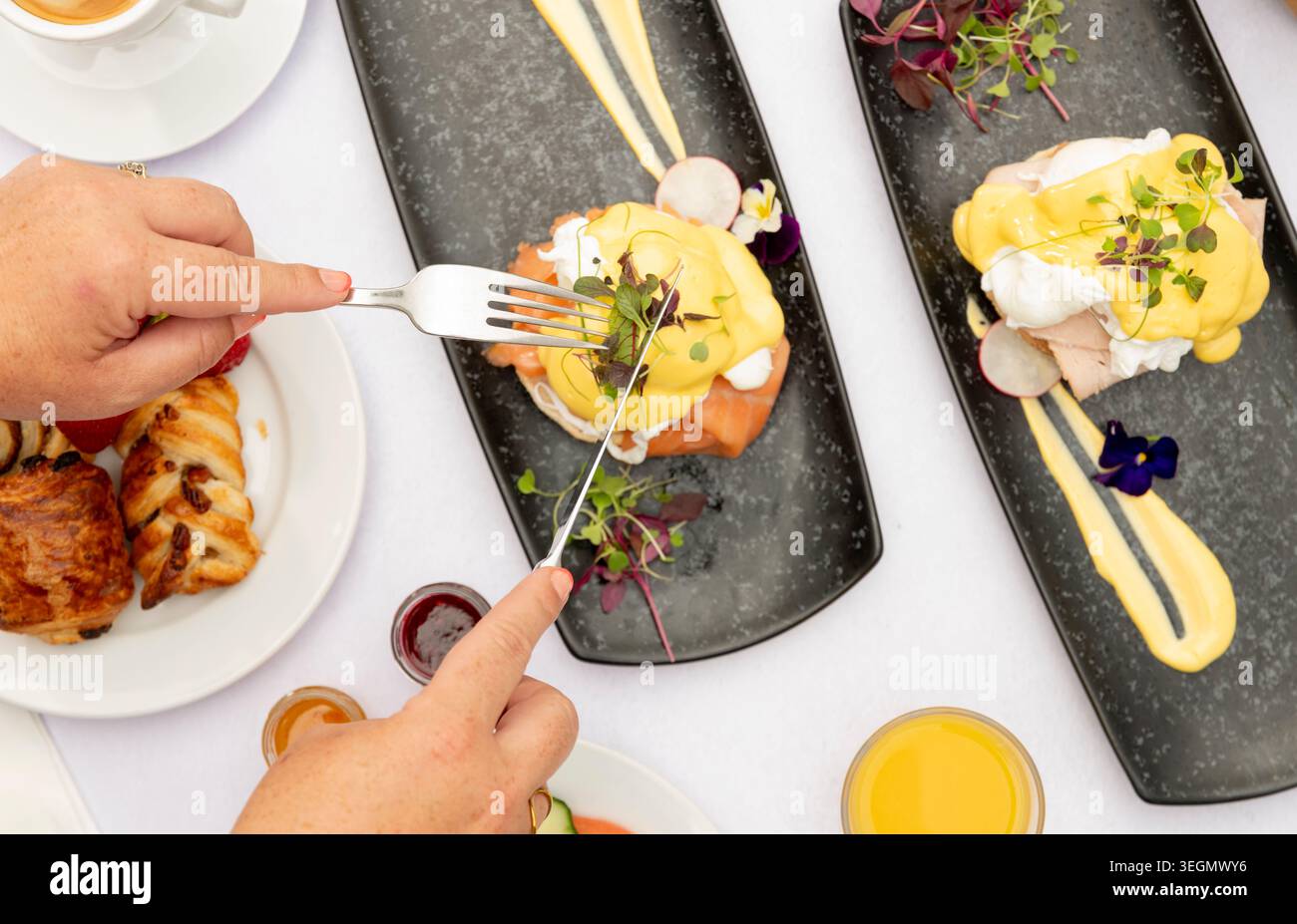 Délicieux brunch avec œufs Benedict et pâtisseries fraîches servis dans un cadre vibrant Banque D'Images
