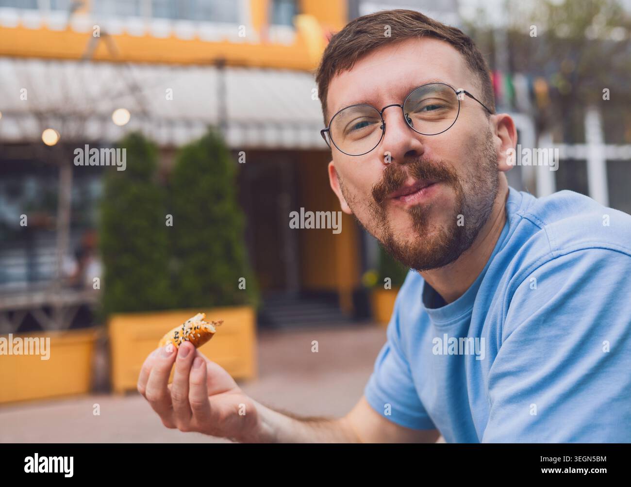 Un jeune homme aime manger de la nourriture de rue. Banque D'Images