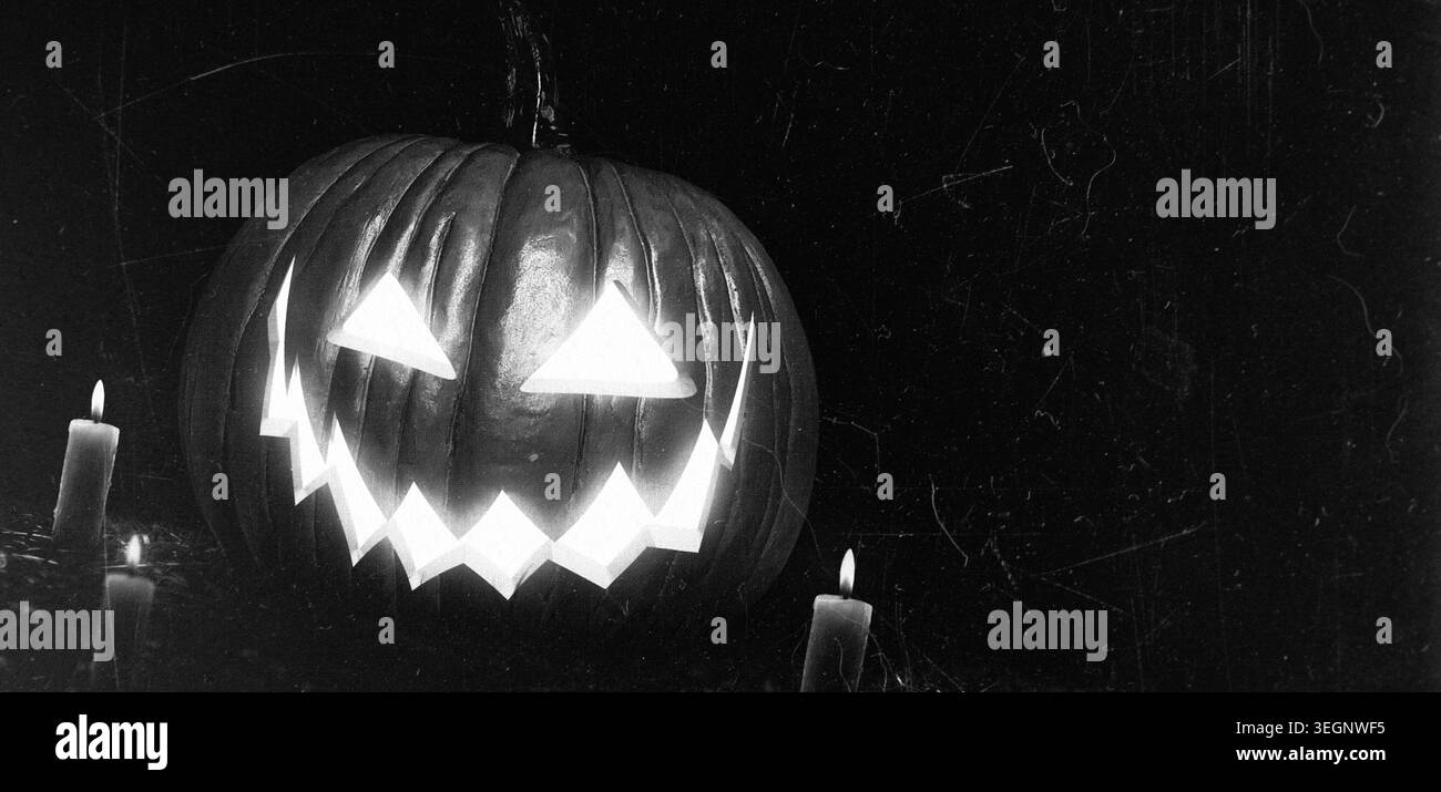 Citrouille d'halloween sculptée effrayante avec des bougies allumées dans un style grunge foncé Banque D'Images