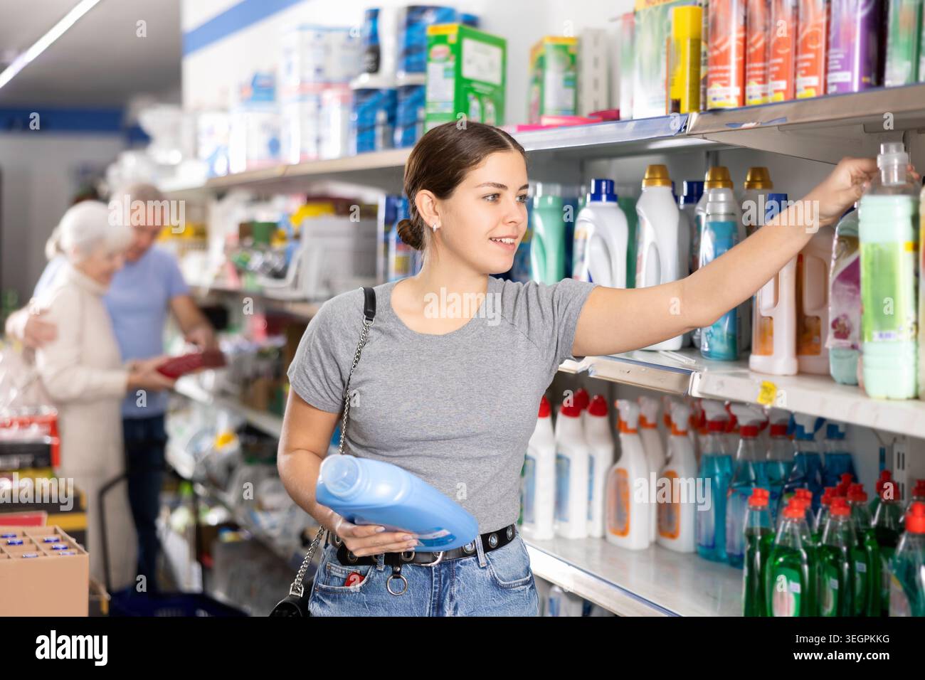 Jeune femme acheteuse choisissant le détergent liquide dans le grand supermarché Banque D'Images
