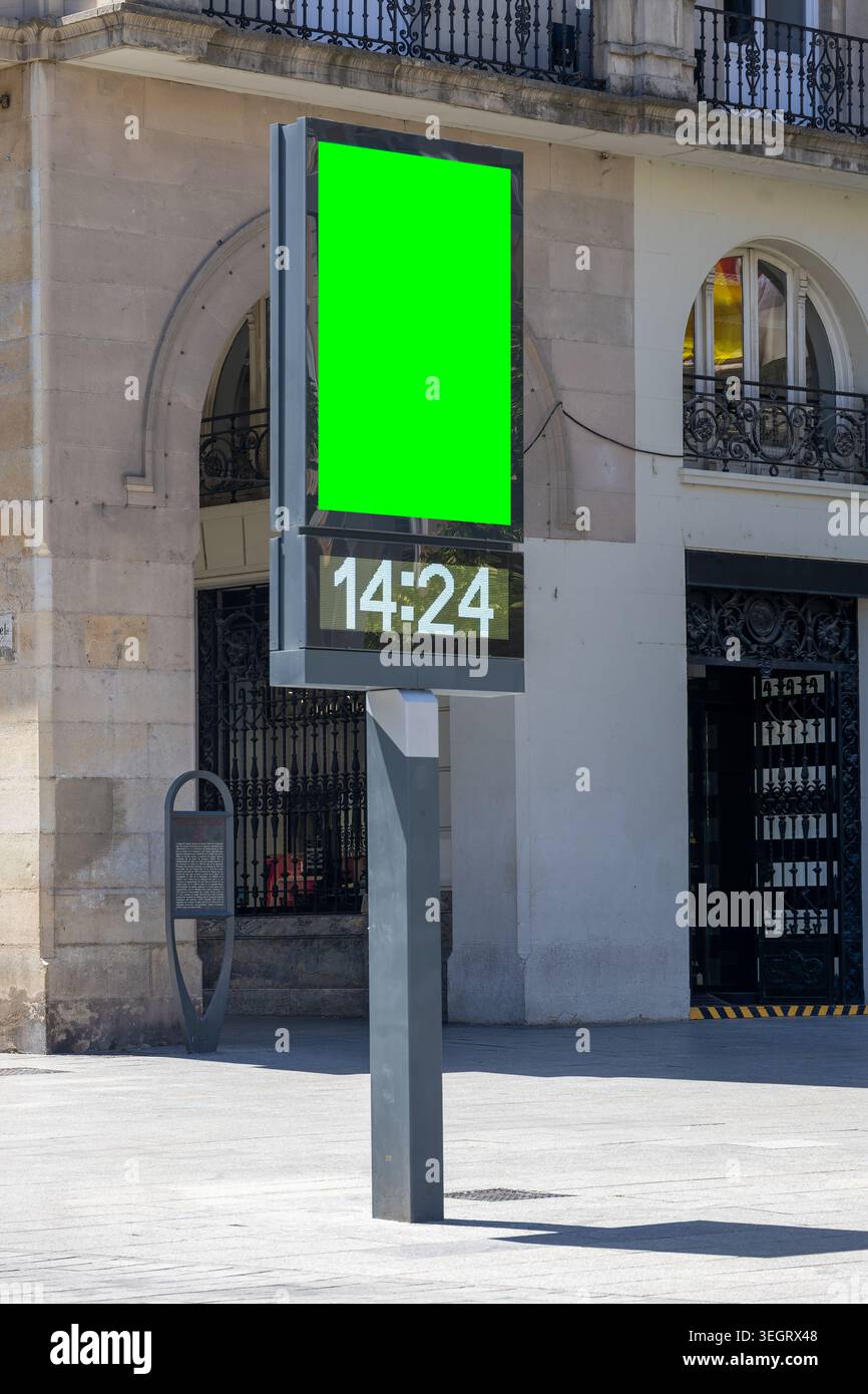 Kiosque TOTEM d'information extérieur avec affichage vert chroma key et horloge numérique LED montrant le temps 14 :24 contre la façade de l'ancien bâtiment. Cadre urbain blen Banque D'Images