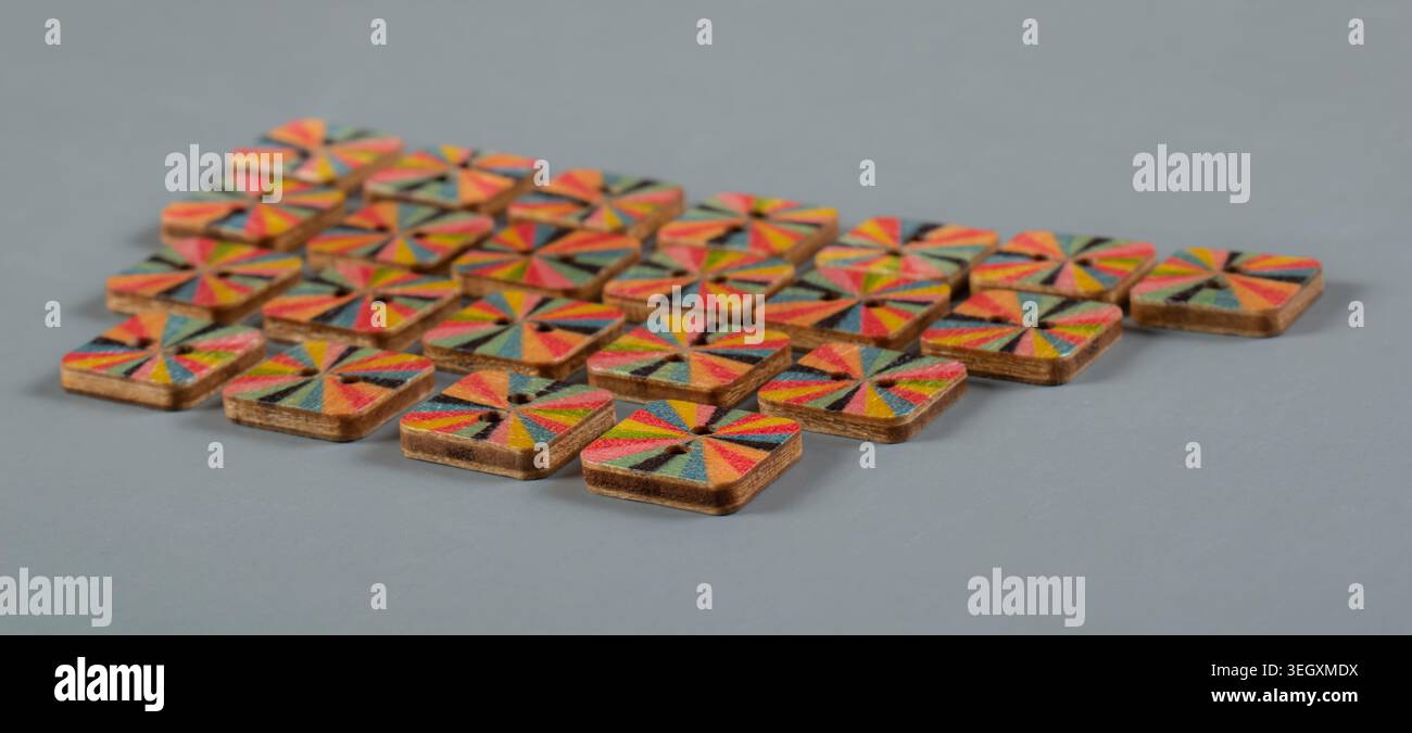 Boutons en bois colorés fabriqués à la main disposés sur fond gris pour la couture, l'artisanat textile et les accessoires de mode Banque D'Images