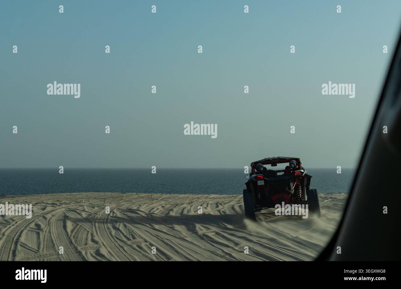 Un plan d'action POV à mise au point sélective avec flou de mouvement créatif, montrant un buggy de sable conduisant sur les hautes dunes du désert surplombant la mer au Qatar. Banque D'Images