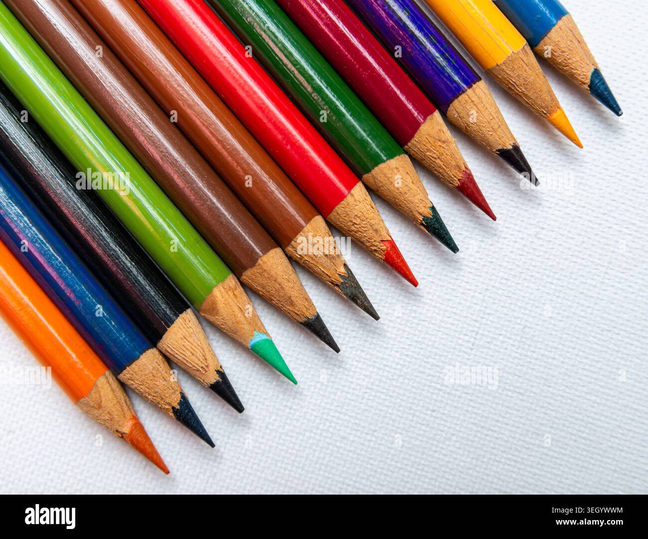 Les crayons de couleur sont alignés sur une surface blanche plate avec des pointes pointues visibles. Chaque crayon a une couleur et un design différents. Banque D'Images