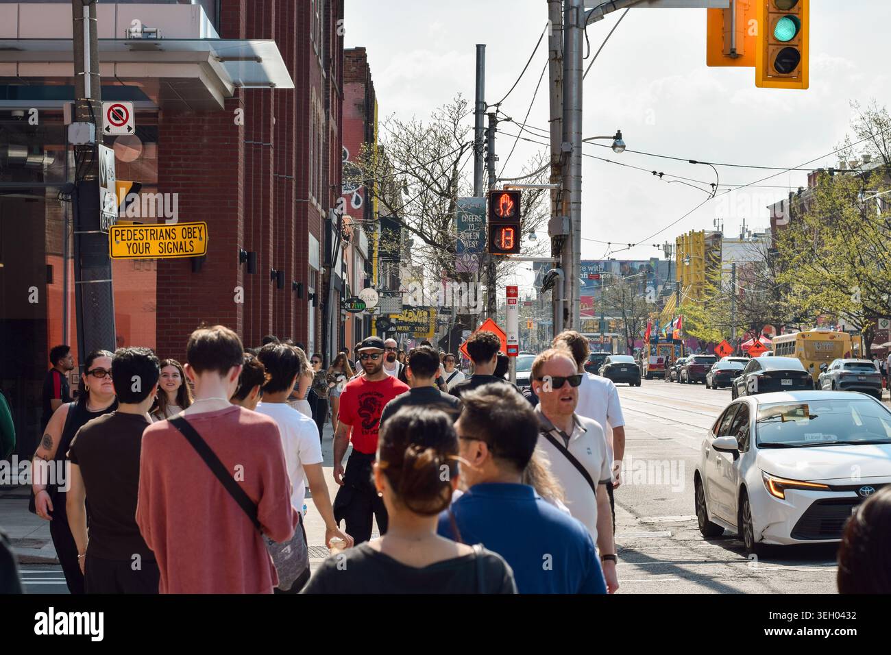 Toronto, Ontario, Canada - 17 mai 2026 : foule de piétons traversant un passage pour piétons sur la rue Queen au centre-ville de Toronto avec signal de compte à rebours, rouge h Banque D'Images