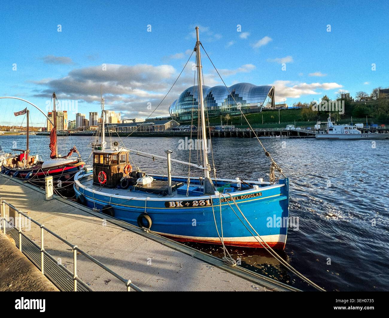 Scène de rivière sereine. Quai urbain paisible avec des bateaux et des eaux réfléchissantes au coucher du soleil Banque D'Images
