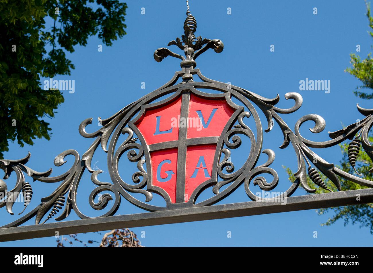 Gros plan des armoiries historiques de Lugano, en Suisse, avec un écusson rouge avec des lettres LVGA à l'intérieur d'une porte en fer forgé noir ornée. CLE Banque D'Images