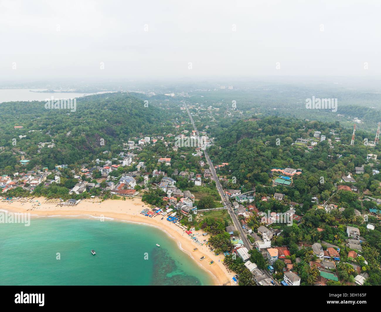 Vue aérienne de la plage d'Unawatuna avec de l'eau turquoise et des bâtiments côtiers nichés au milieu d'une végétation tropicale luxuriante à Unawatuna, Province du Sud, Sri la Banque D'Images