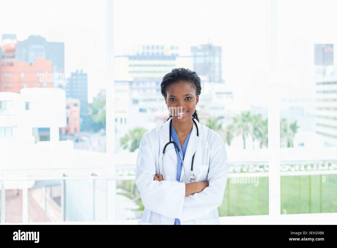 Médecin afro-américain debout centré dans la clinique portant une blouse de laboratoire blanche et un stéthoscope Banque D'Images
