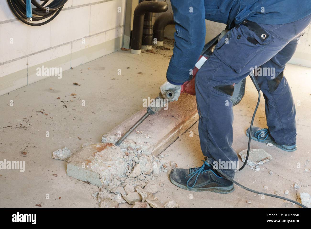 Travailleur utilisant un marteau perforateur pour briser le plancher de béton pendant la rénovation Banque D'Images