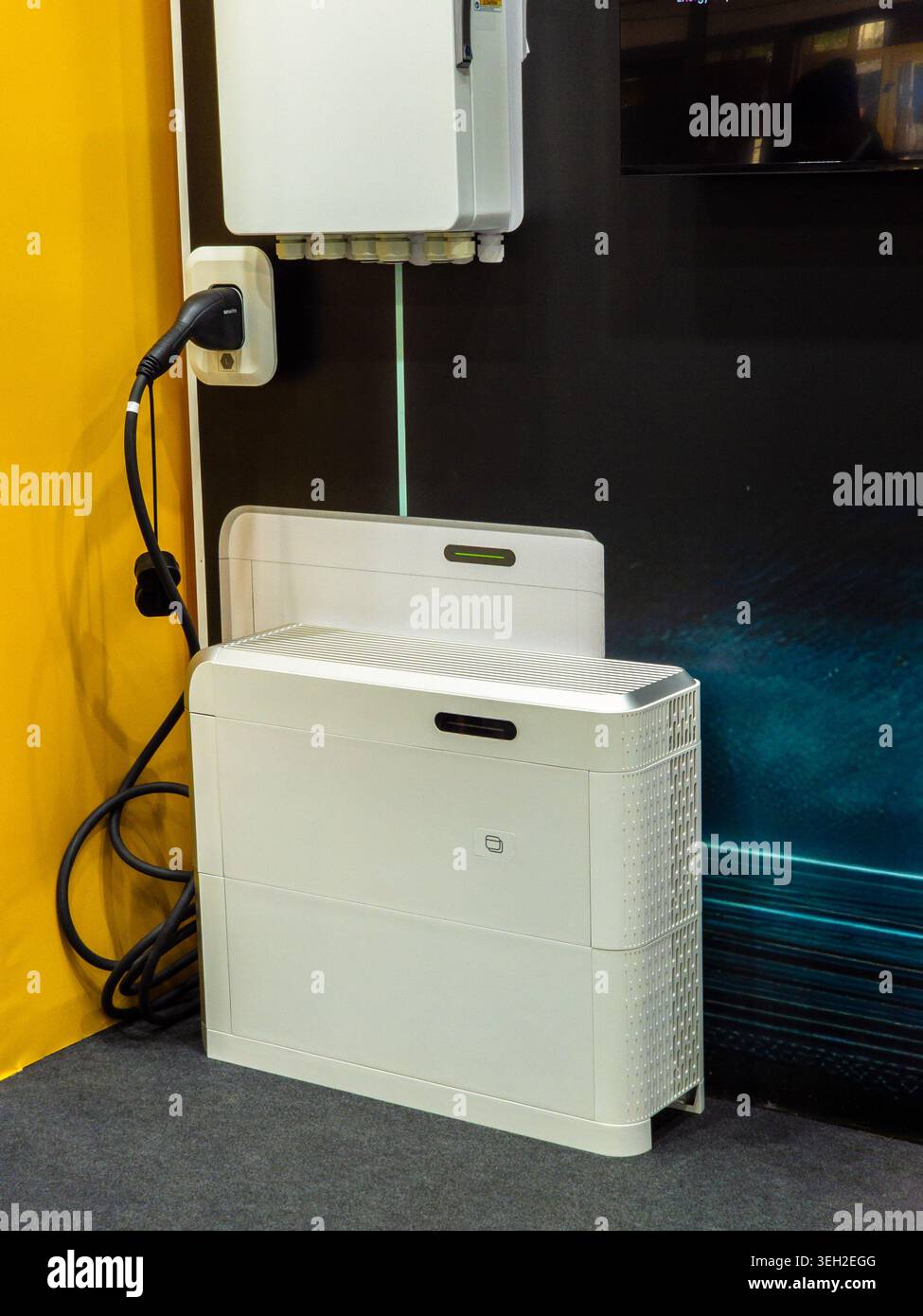 L'invention concerne une unité de batterie résidentielle contemporaine de stockage d'énergie qui se trouve sur le sol à côté d'une station de charge de véhicule électrique et d'un boîtier de commande. Banque D'Images