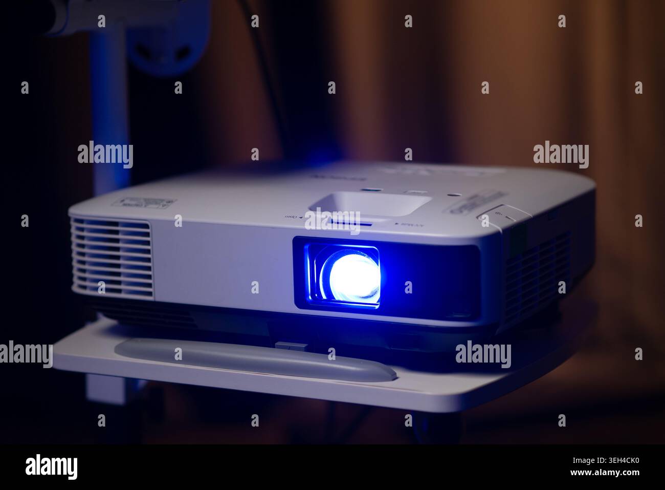 Projecteur multimédia moderne avec une lumière bleue éclatante dans une pièce sombre en gros plan Banque D'Images
