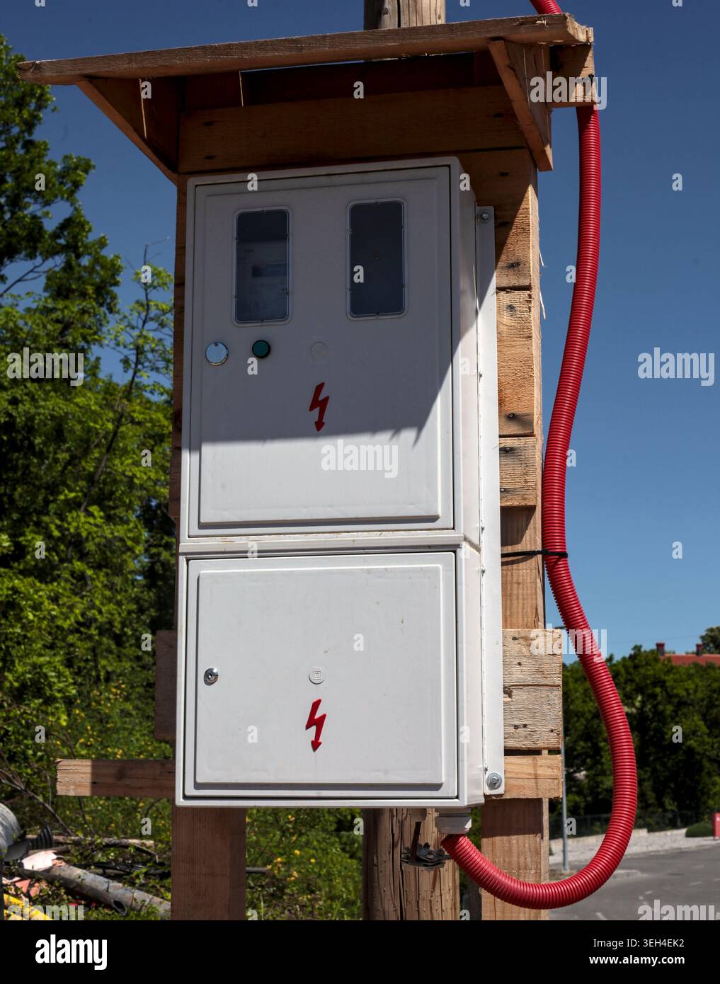 Boîte de compteur électrique industrielle extérieure montée sur une structure de poteau en bois sous un ciel bleu clair. Banque D'Images