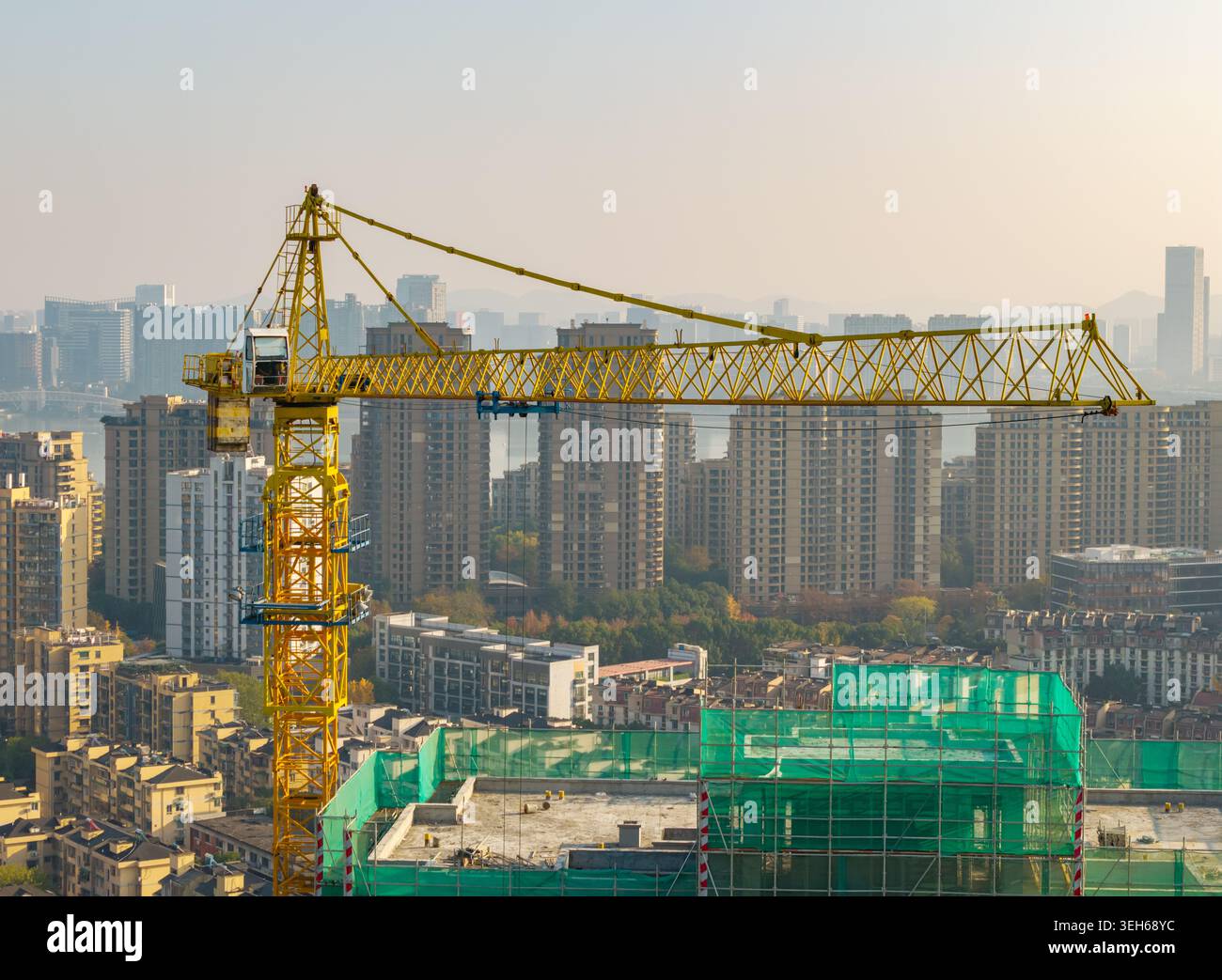 Grue à tour jaune vibrante travaillant sur un projet de construction dans une ville moderne animée Banque D'Images