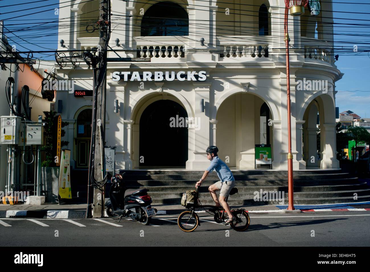 Un cycliste passant devant une succursale Starbucks dans la vieille ville, Phuket Town, Thaïlande, construit dans le style traditionnel sino-portugais (Peranakan) Banque D'Images