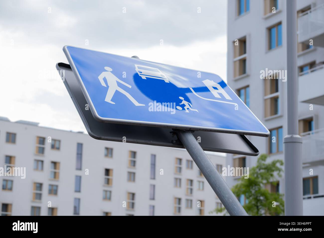 Panneau de signalisation bleu pour les piétons, les cyclistes et les véhicules installés devant des immeubles d'appartements contemporains dans une distri urbaine moderne Banque D'Images