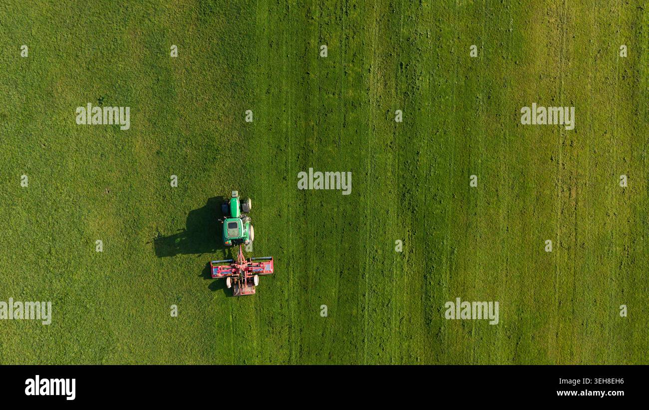 Vue aérienne de haut en bas du tracteur fauchant l'herbe dans le parc de la ville avec espace de copie Banque D'Images