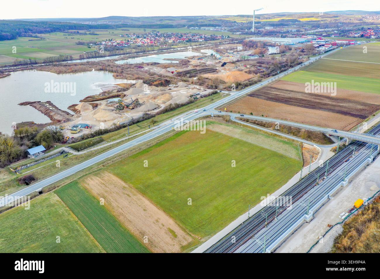 Vue aérienne d'une gravière et d'un site industriel près d'une rivière entourée de champs verdoyants et de la ville de Buttenheim, Bavière, Allemagne. Banque D'Images