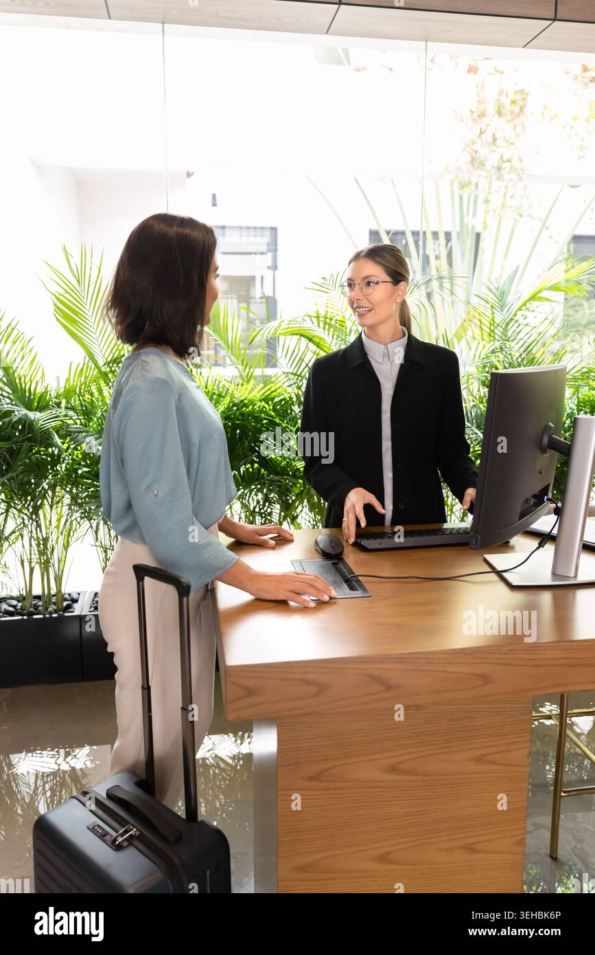Femme hôtesse avec valise debout à la réception Banque D'Images