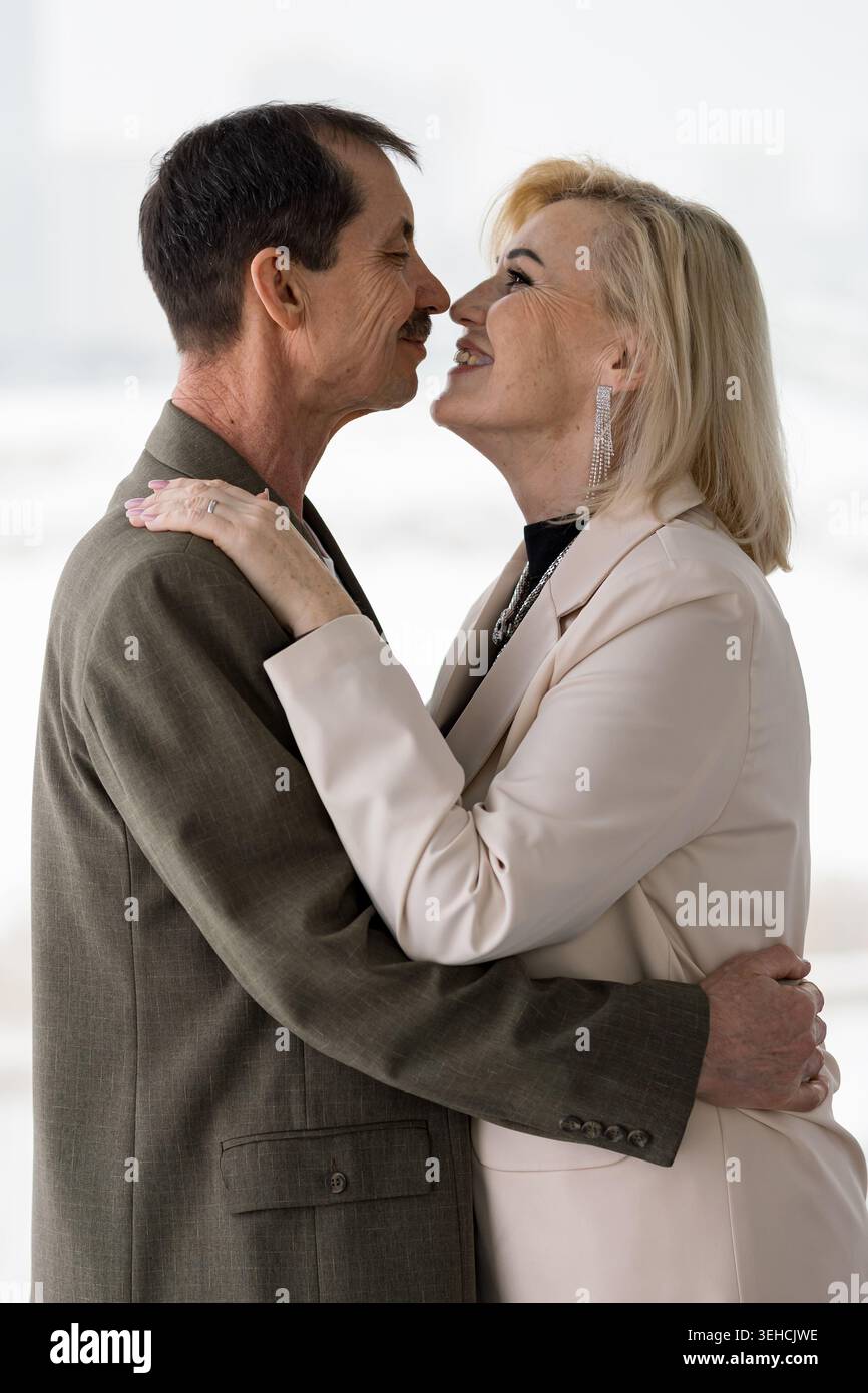 Tendre couple caucasien s'embrassant dans le bureau, professionnels matures partageant la réunion tranquille près de la fenêtre, Blazer et costume tenue, regard doux et front Banque D'Images