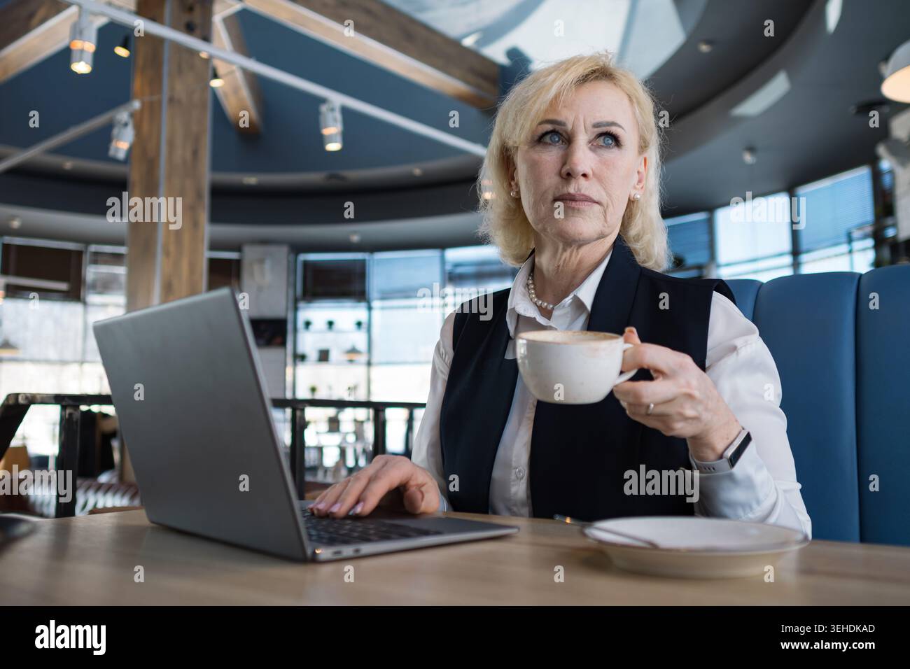 Femme d'affaires appréciant la pause café. Femme âgée avec café et ordinateur portable. Une femme plus âgée prend une pause rapide pendant une journée de travail chargée. Femme d'affaires senior Banque D'Images