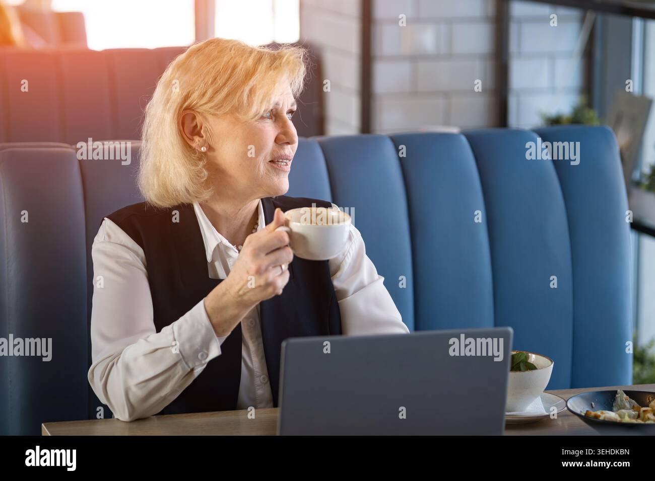 La femme calme observe le paysage urbain. Femme senior en tenue d'affaires contemplant la vue sur la ville paisiblement. Femme mature dans les merveilles formelles de vêtements à Urban Banque D'Images