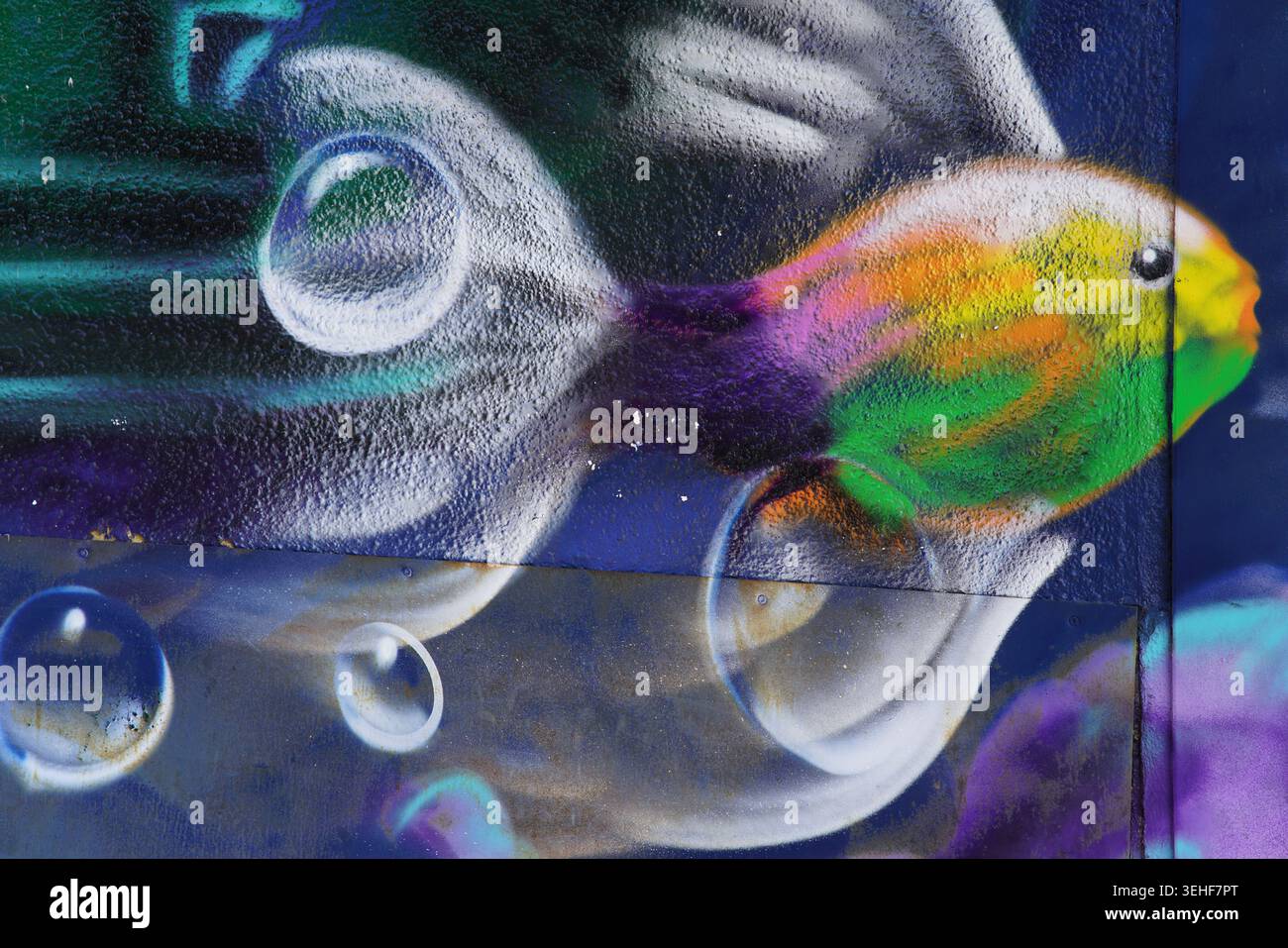 Poissons colorés arc-en-ciel dynamiques nageant avec des bulles transparentes peinture murale détaillée sur fond sombre à Brighton, en Angleterre. Banque D'Images