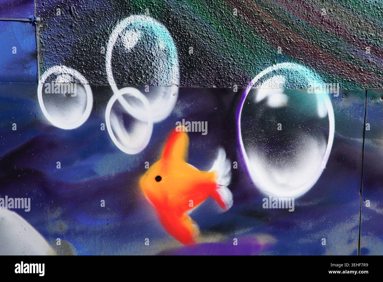 Poisson rouge orange éclatant nageant avec de grandes bulles transparentes réalistes en bleu profond et violet peinture murale détaillée d'art de rue à Brighton, en Angleterre Banque D'Images