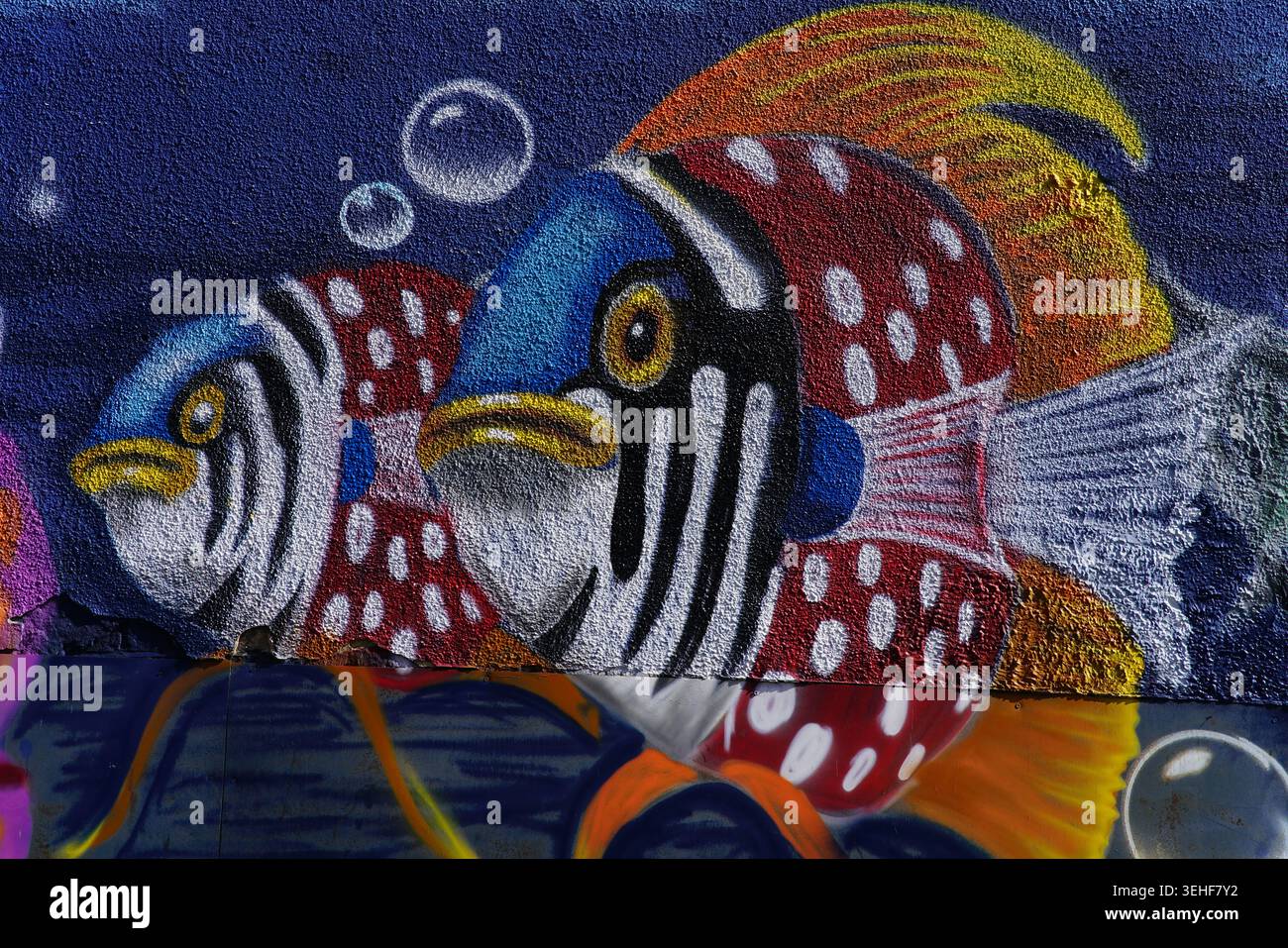 Poisson tropical rayé rouge et blanc éclatant avec des têtes bleues vives et des yeux jaunes nageant avec des bulles Street art mural détaillé.Brighton, Angleterre Banque D'Images