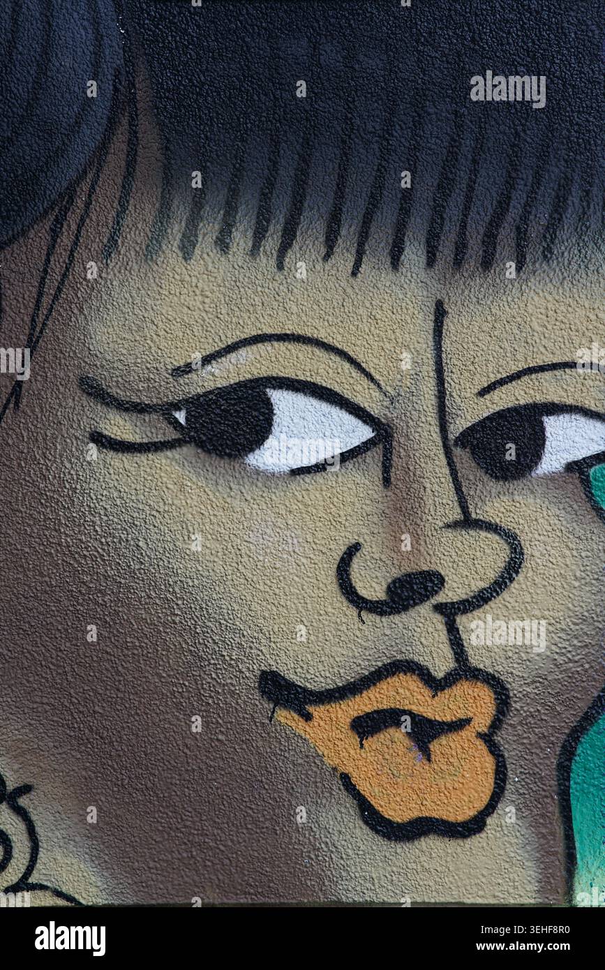 Portrait en gros plan stylisé d'une femme aux lèvres orange frappantes, aux cheveux noirs audacieux et aux yeux expressifs dans une murale de Street art vibrante à Brighton, en Angleterre. Banque D'Images