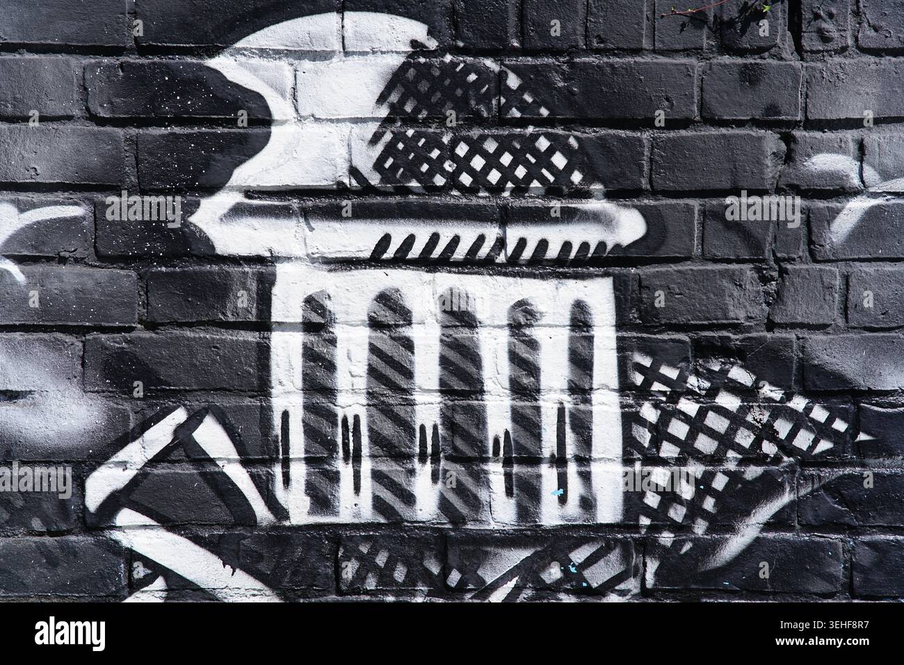 Peinture murale noire et blanche audacieuse représentant un monument classique avec des colonnes et des motifs à damier sur un mur de briques sombres à Brighton, en Angleterre. Banque D'Images