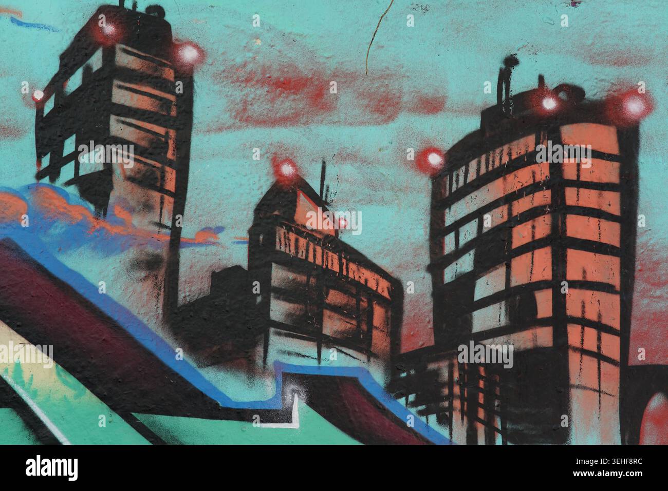 Peinture murale de rue urbaine vibrante avec des lumières rouges brillantes sur de hauts bâtiments contre un ciel turquoise par l'artiste NGO à Brighton, en Angleterre. Banque D'Images