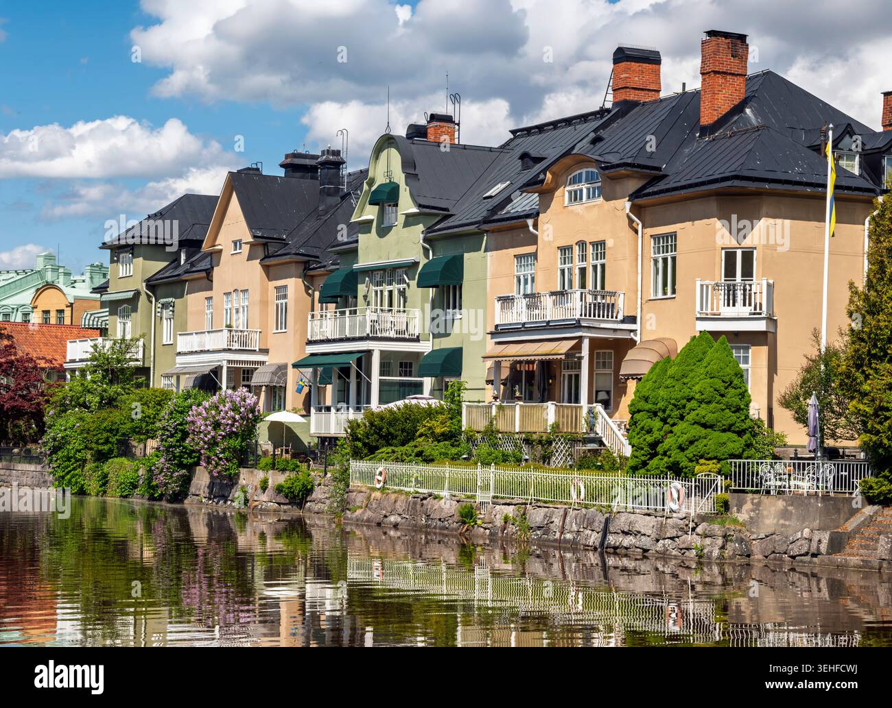Maisons colorées en bord de mer le long de la rivière Svartån à Örebro, Suède, par une journée d'été ensoleillée avec des reflets dans l'eau calme. Banque D'Images