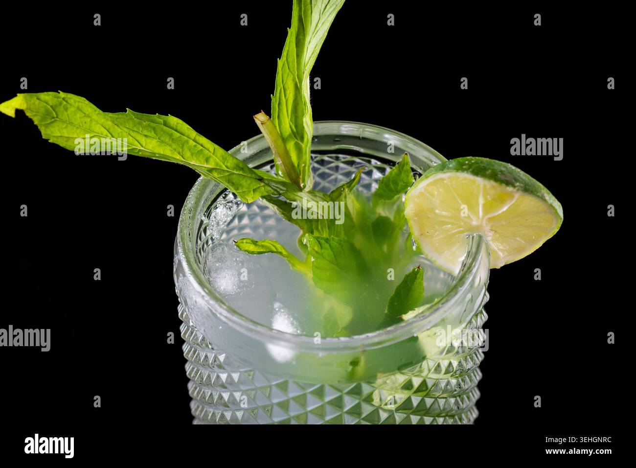 Cocktail de mojito frais avec des feuilles de menthe citron vert et de la glace sur fond noir Banque D'Images