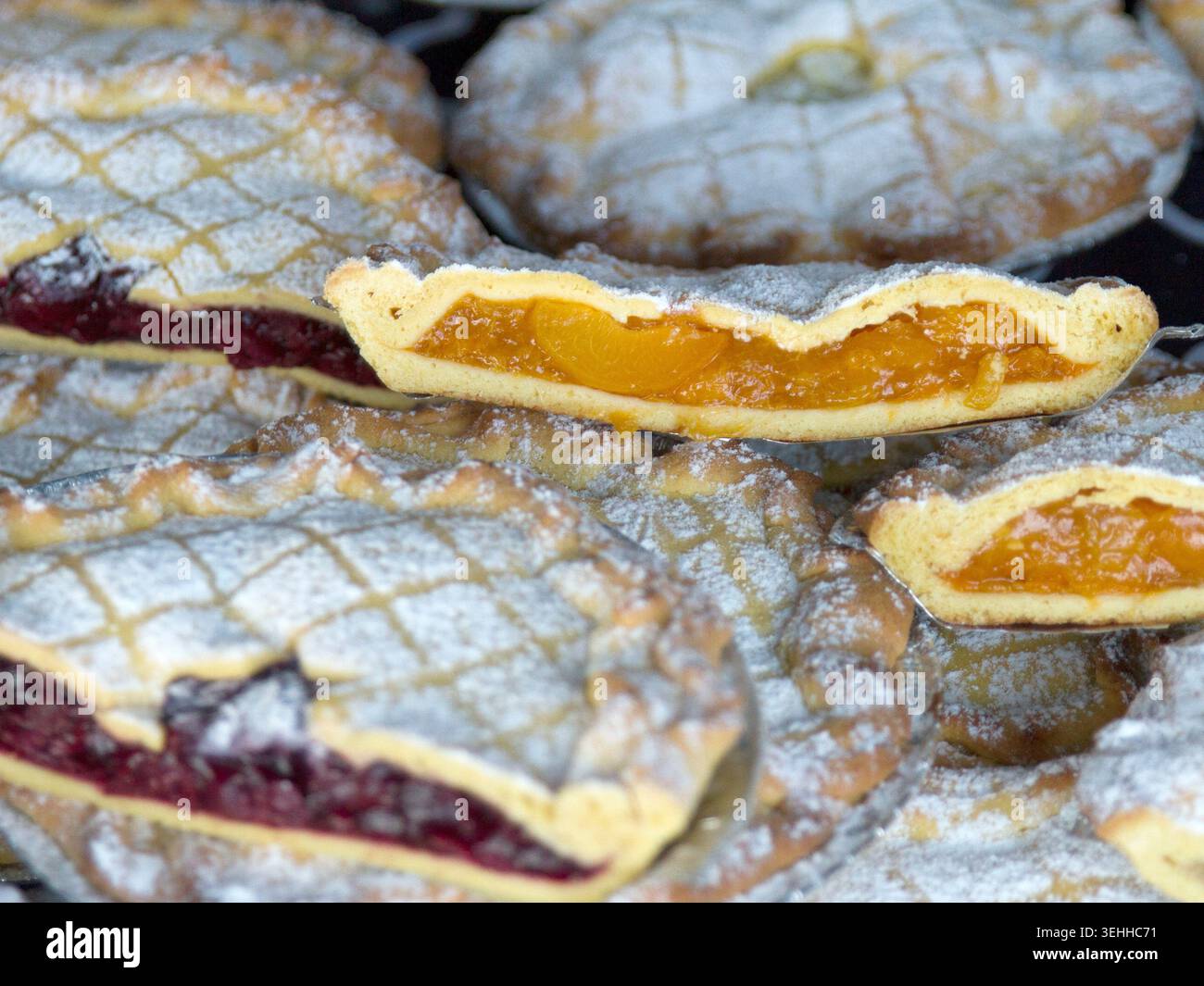 Vue rapprochée de tartes crostata aux fruits en treillis fraîchement cuites garnies de confiture d'abricot et de baies noires saupoudrées de sucre glace. Banque D'Images