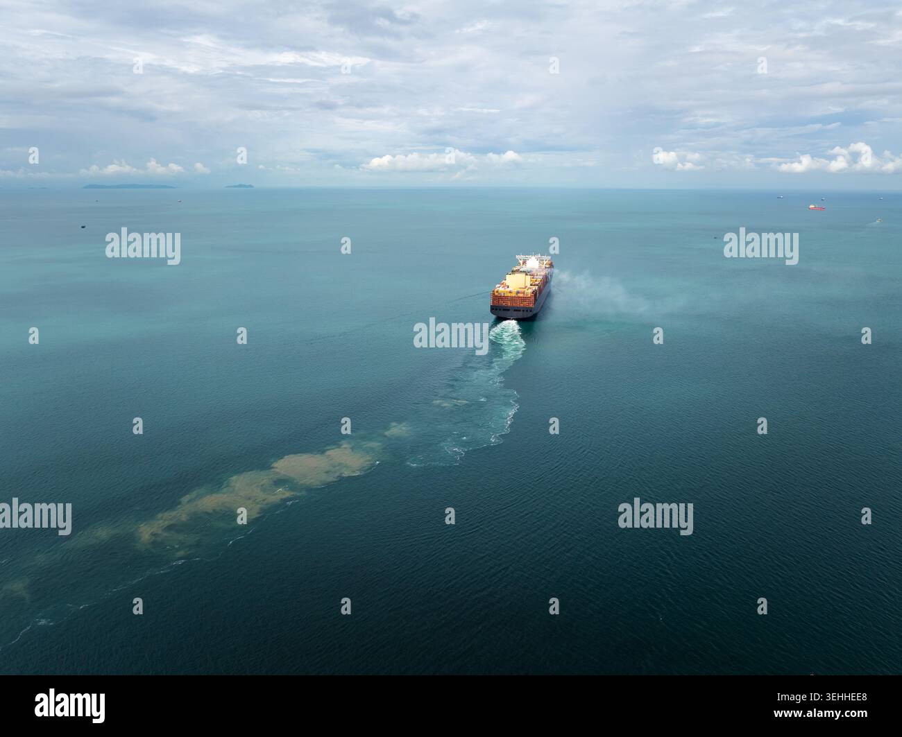 Un porte-conteneurs navigue dans les eaux côtières profondes illustrant les thèmes de la logistique maritime et de la chaîne d'approvisionnement du commerce mondial près de sattahip thaïlande. Banque D'Images