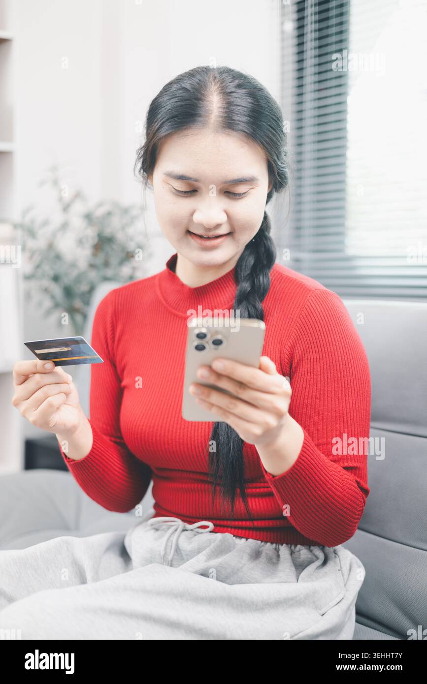 Jeune femme asiatique détenant une carte de crédit et un smartphone pour les achats en ligne à la maison, le paiement mobile et le concept d'achat de commerce électronique, la vie fintech sans espèces Banque D'Images