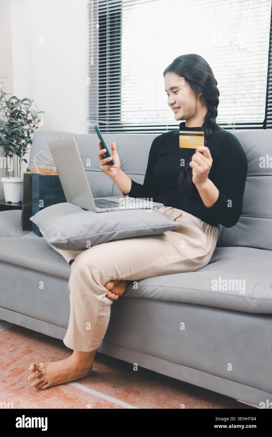 Jeune femme asiatique utilisant smartphone, ordinateur portable et carte de crédit pour les achats en ligne à la maison, paiement mobile de commerce électronique, achat sans espèces, consommateur numérique Banque D'Images