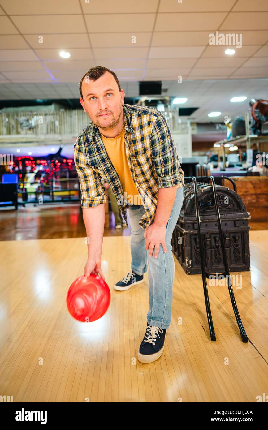 Homme bowling avec balle rouge dans l'allée intérieure Banque D'Images