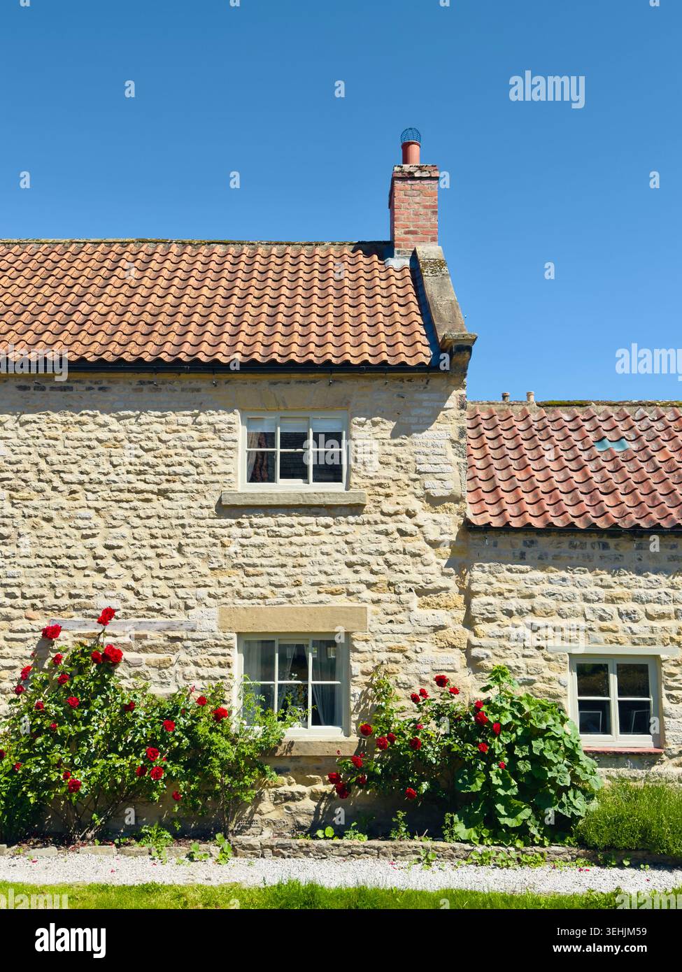 Pittoresque cottage en calcaire avec des rosiers grimpants et des tuiles de toit en terre cuite dans la ville historique de Helmsley, North Yorkshire, Angleterre. Banque D'Images