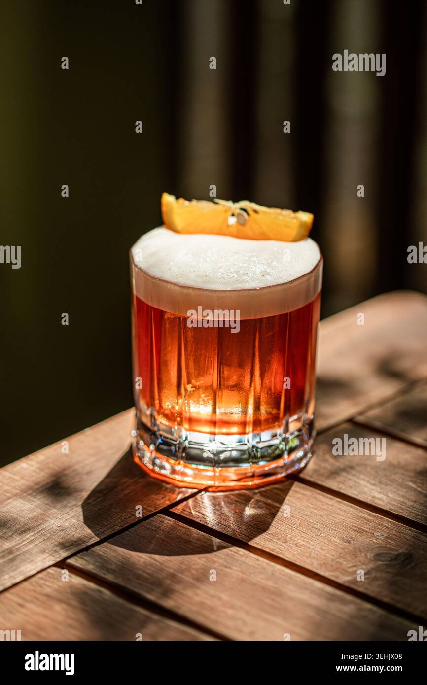 Cocktail ambre avec mousse et écorce d'orange Banque D'Images