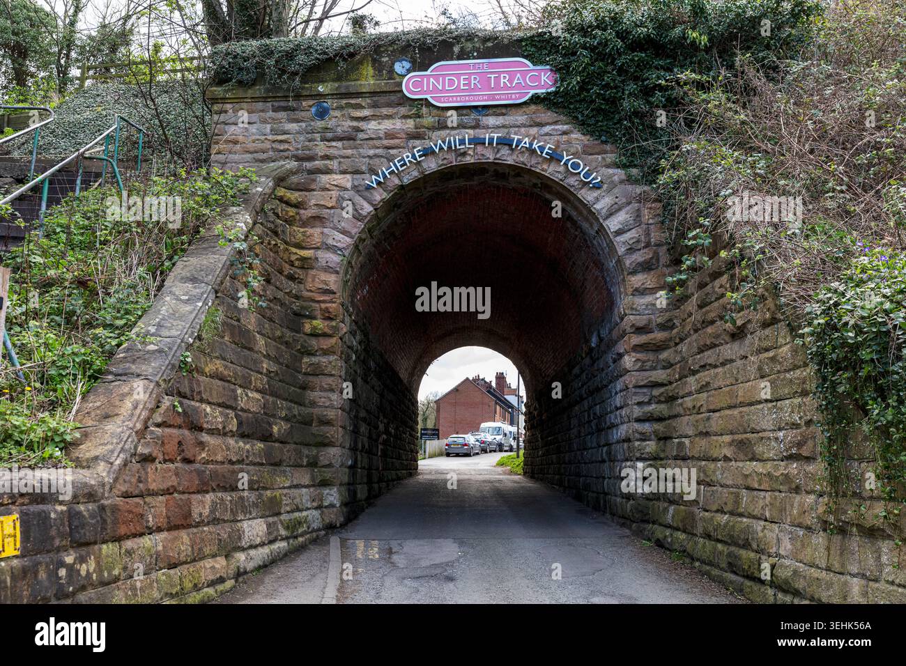 Une arche en pierre marquant l'entrée de la Cinder Track à Whitby, North Yorkshire. Le tunnel en briques altérées est entouré de verdure, avec du lierre Banque D'Images