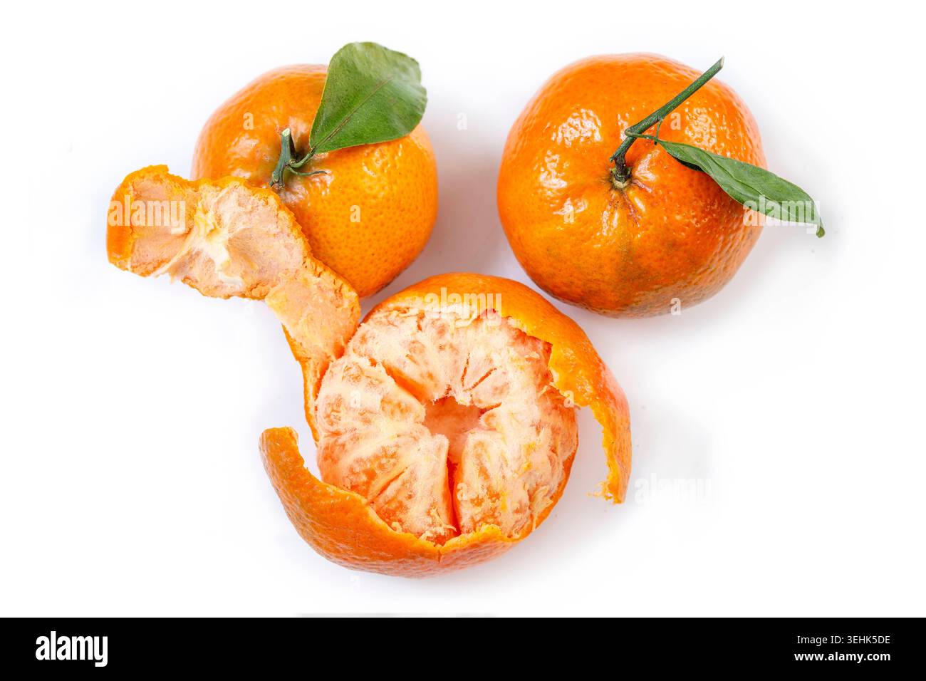 Deux mandarines entières Citrus reticulata avec des feuilles et une mandarine pelée sont positionnées sur un fond blanc. Mandarines. BSIP_016938_041 Banque D'Images