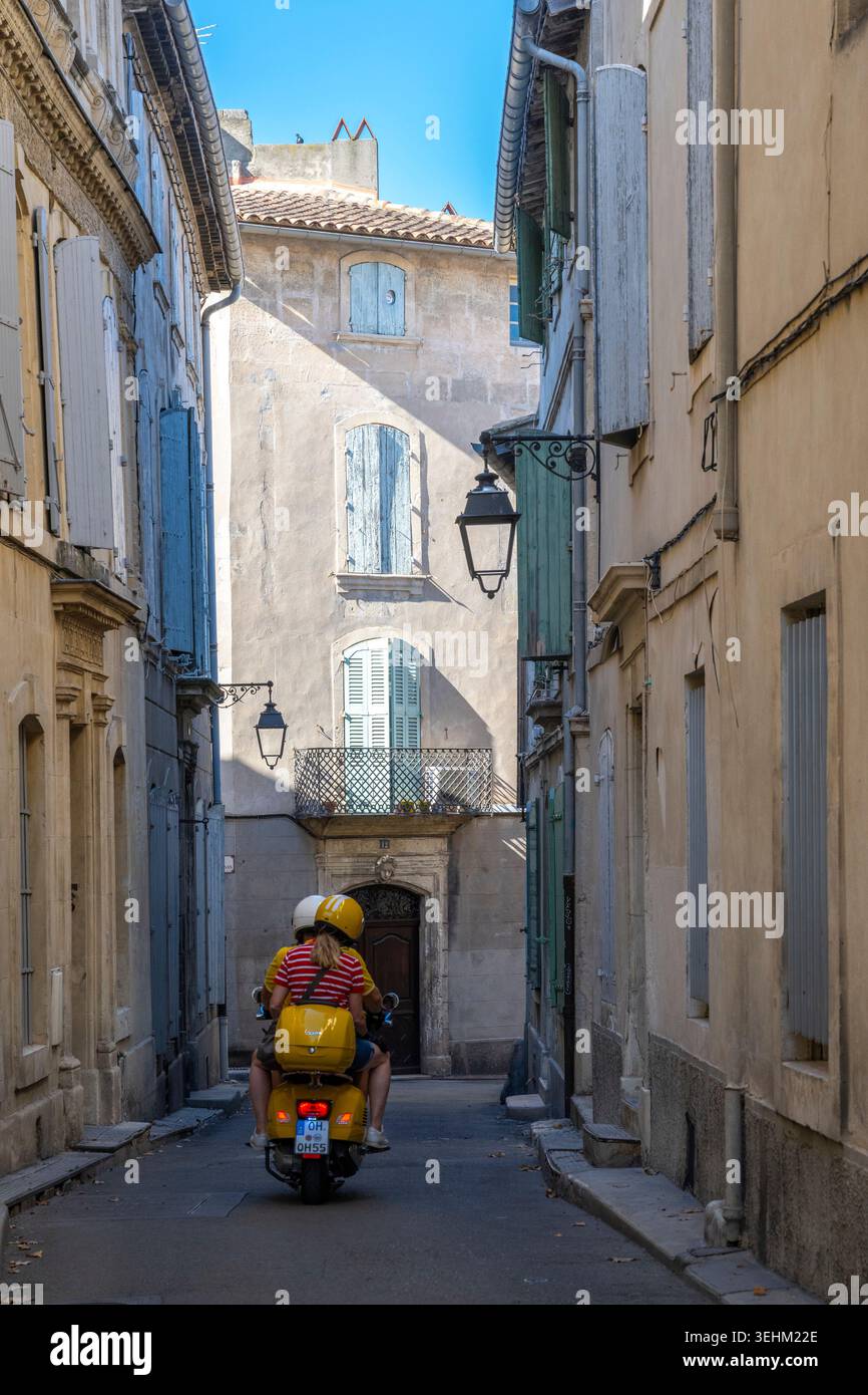 Scène de rue, jeune couple sur scooter à moteur dans la vieille partie d'Arles, France Banque D'Images