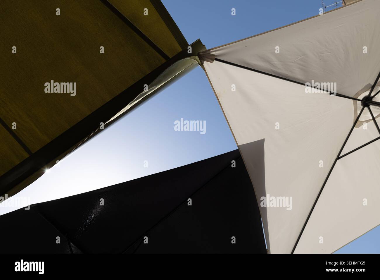 Vue abstraite de parapluies de marché se chevauchant contre un ciel bleu. Banque D'Images