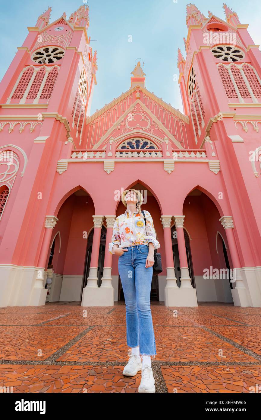 Vue en bas angle d'un voyageur debout devant une basilique néo-gothique rose à Jerico, Antioquia, Colombie, capturant le charme traditionnel de la ville et l'architecture Banque D'Images