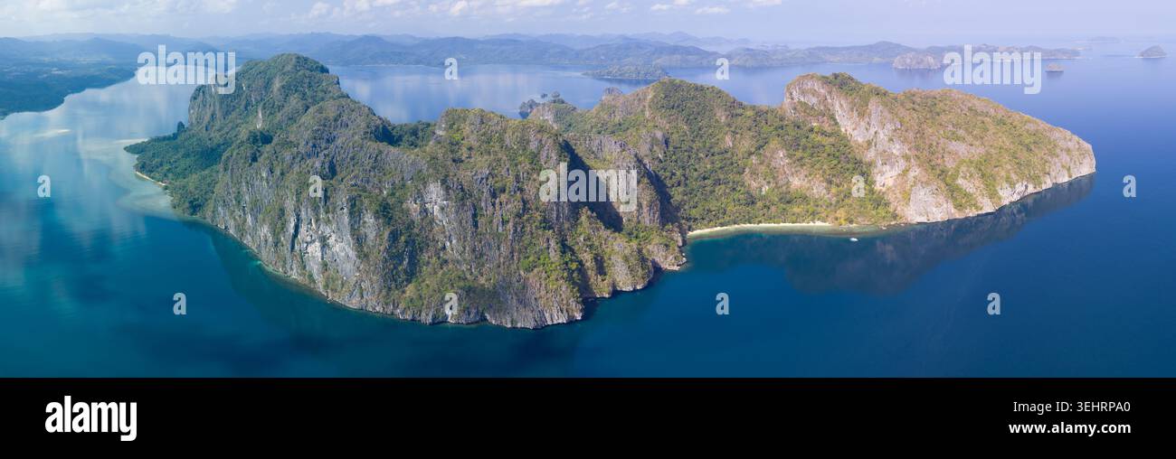 Une eau calme entoure une île de calcaire accidentée à El Nido, aux Philippines. Cette région de Palawan est une destination de vacances populaire en raison de ses paysages. Banque D'Images